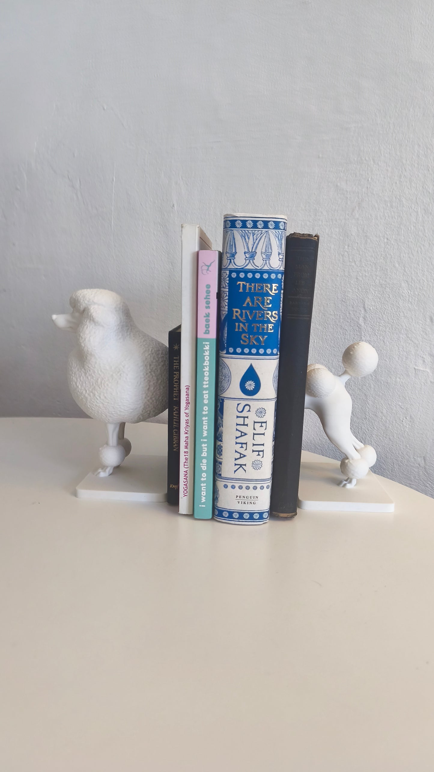 Three books stacked in between a poodle bookend