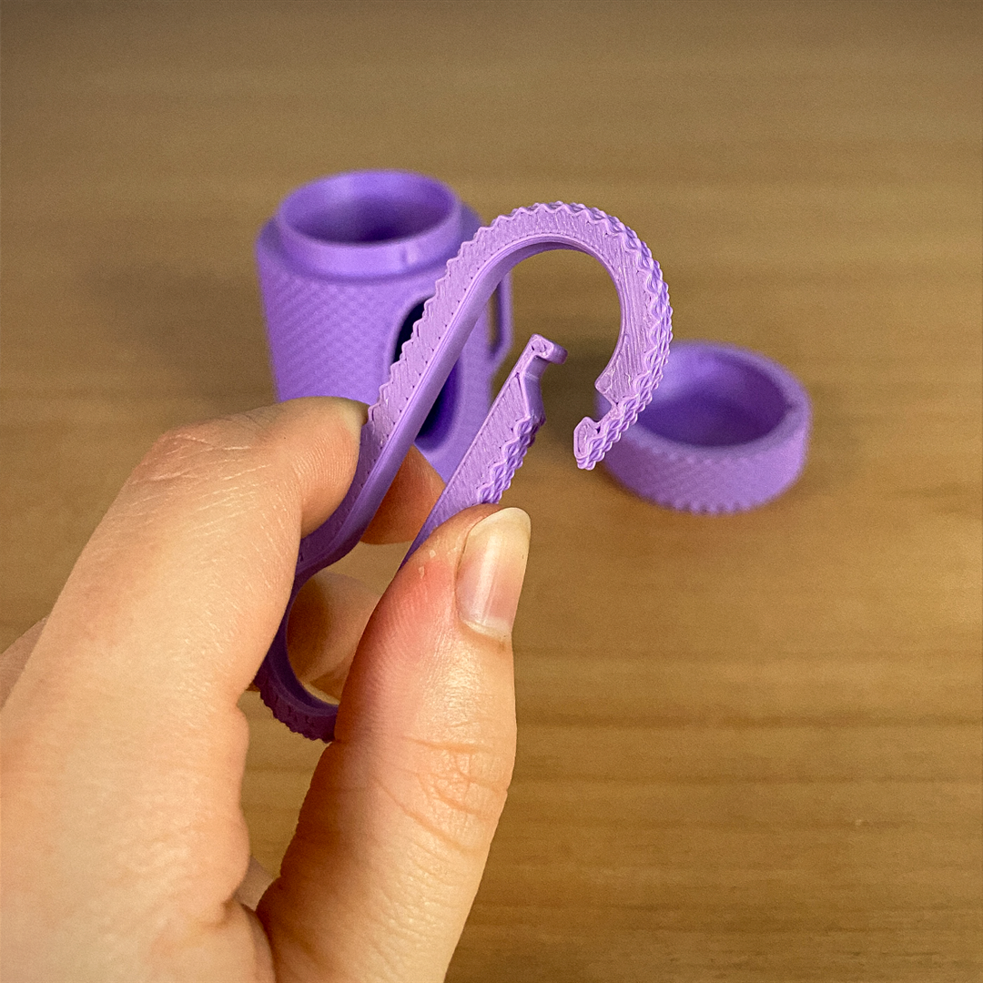Purple silicone ring with a unique design held by a hand on a wooden surface