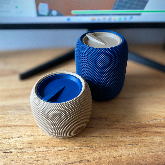 Two small round speakers, one blue and one silver, on a wooden surface with a blurred background.