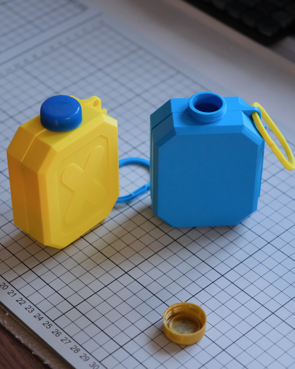 Yellow and blue plastic containers with a small yellow cap on a grid surface.