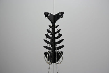 Black metal sculpture resembling a fish on a gray background