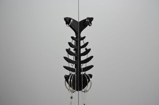 Black metal sculpture resembling a fish on a gray background