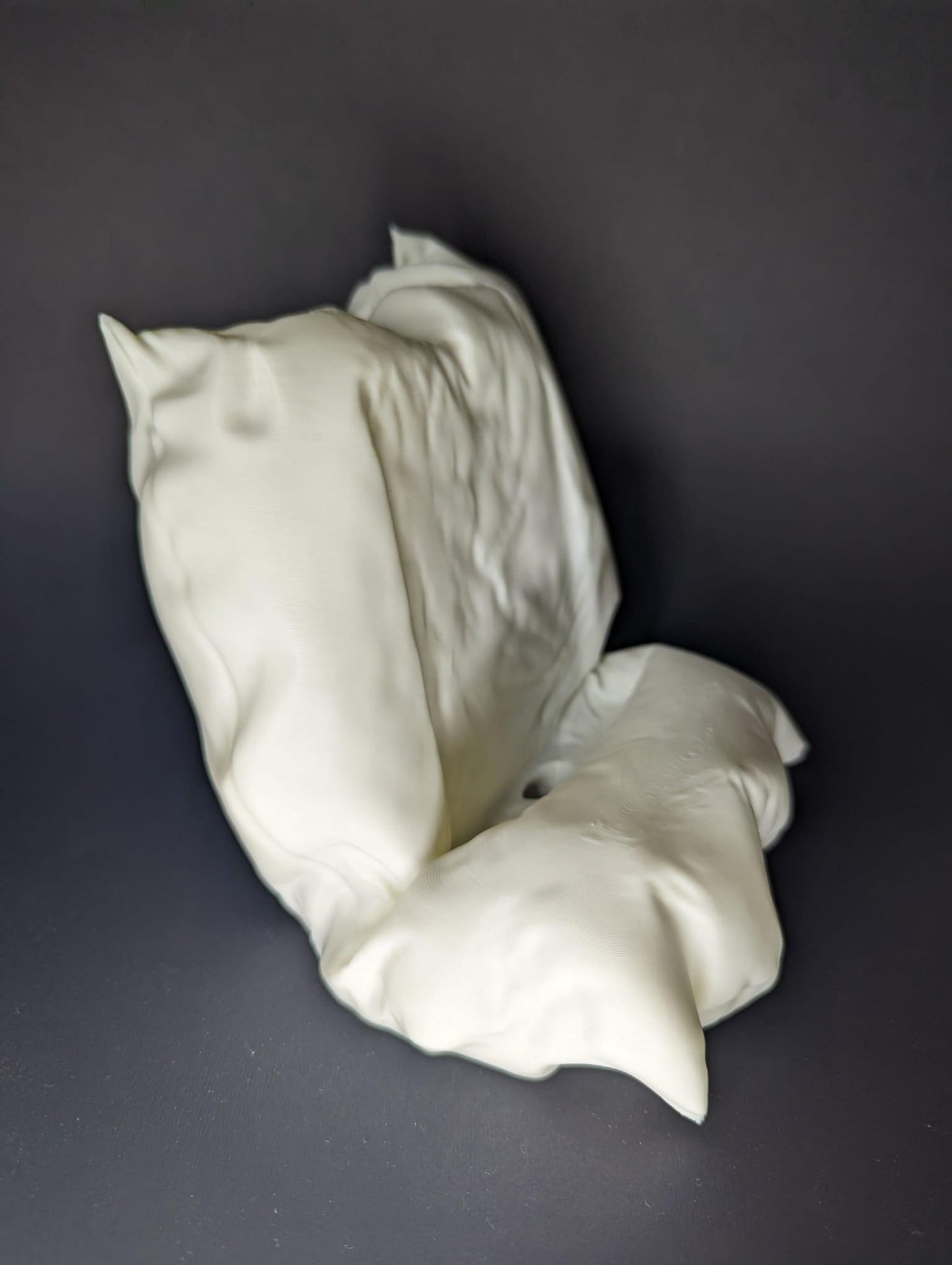 White ceramic sculpture of a flower on a dark gray background