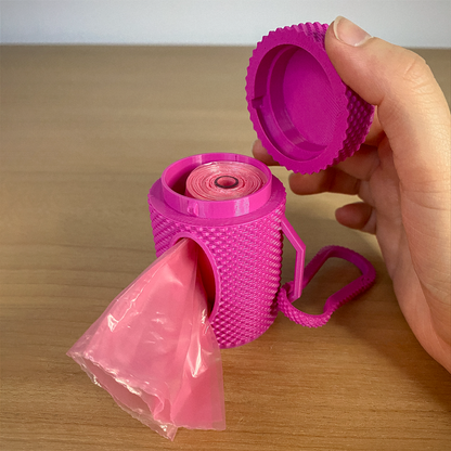 Pink plastic bag dispenser with a hand pulling out a bag on a wooden surface