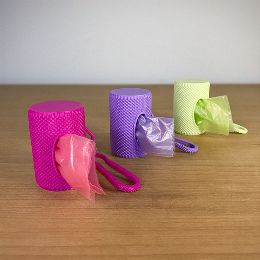 Three textured containers in pink, purple, and green on a wooden surface.