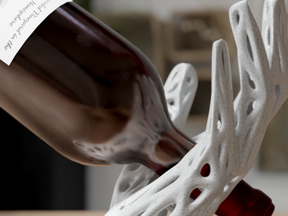 Red wine being poured into a white ceramic wine decanter with intricate design.
