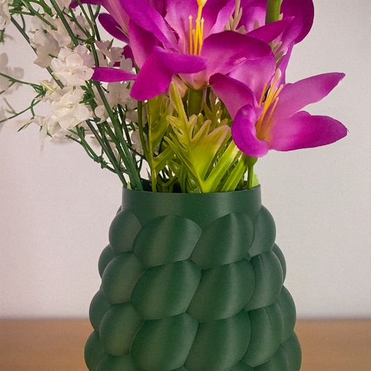 Green textured vase with pink flowers and white flowers on a neutral background