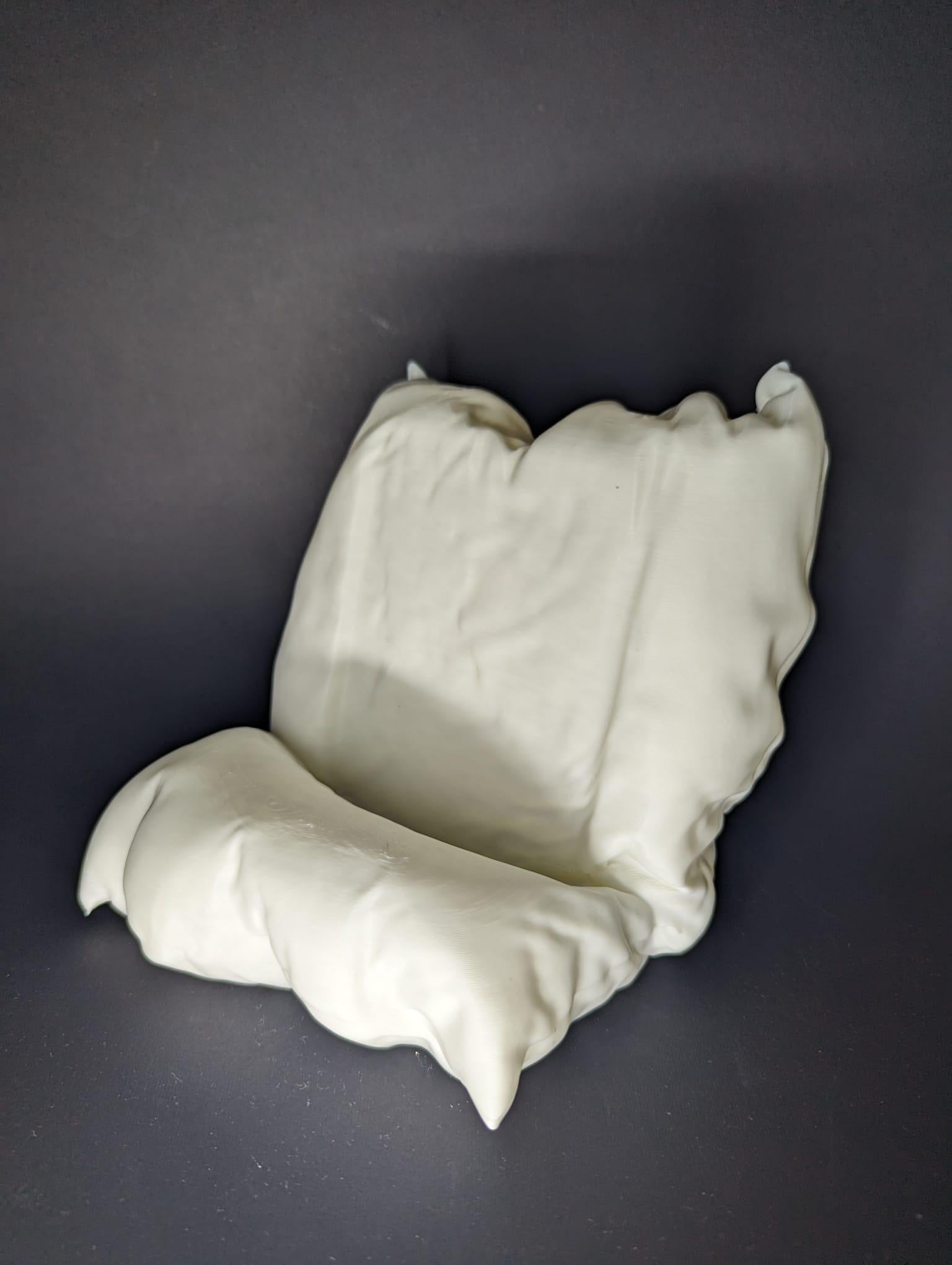 White ceramic sculpture of a chair on a dark gray background
